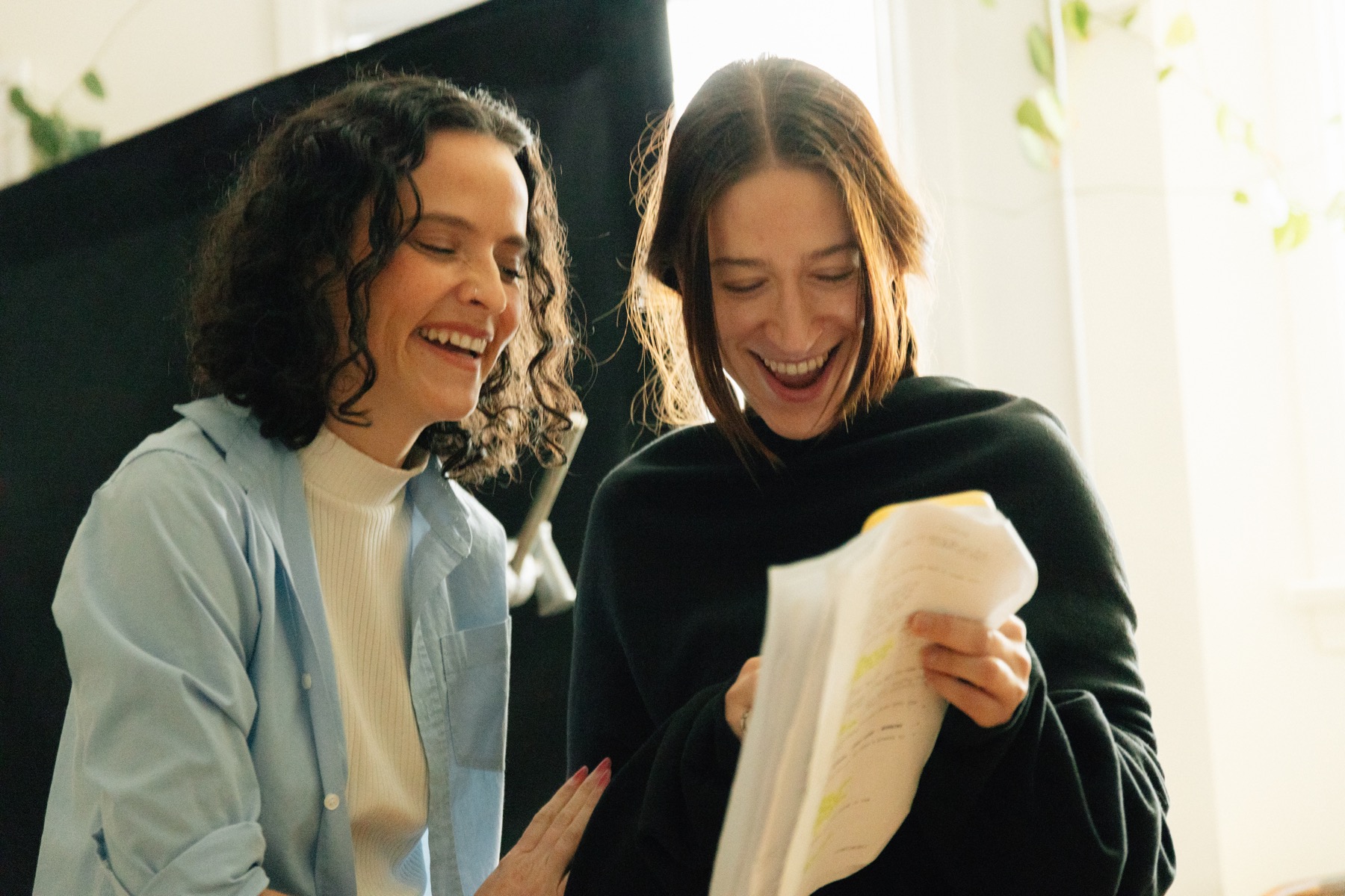 The two actors laughing over their script between takes