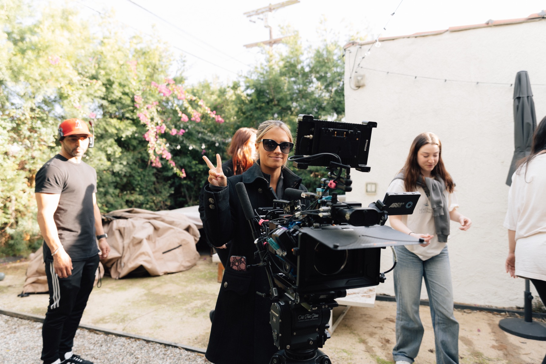 A crew member giving a peace sign beside the film camera